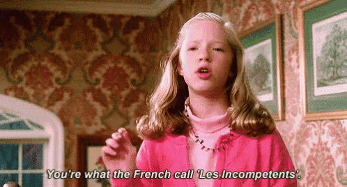 a little girl in a pink sweater is talking to a man in a room .