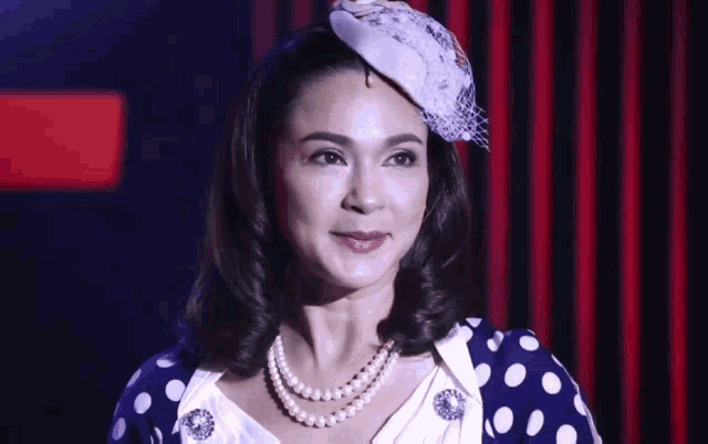 a woman wearing a polka dot dress and a hat is smiling .