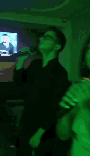 a man is singing into a microphone while a woman looks on