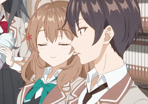 a girl with a red flower in her hair kisses a boy 's cheek