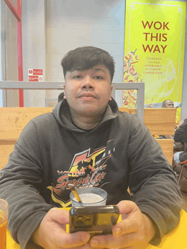 a man sits at a table in front of a wok this way sign