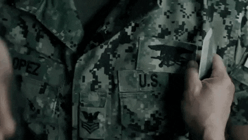 a close up of a person holding a knife in front of a soldier 's uniform .