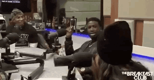 a group of people are sitting at a table with microphones in a room .