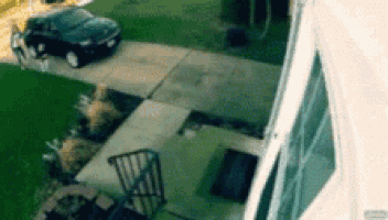 a black car is parked on the side of the road in front of a house