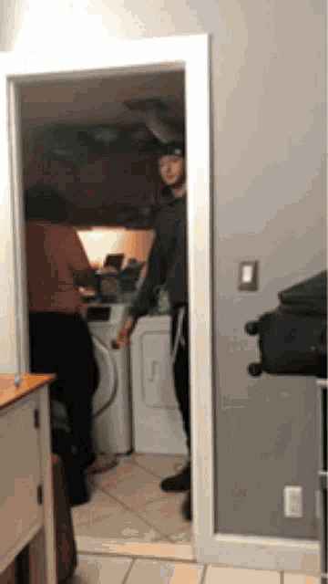a man standing in a laundry room with a washer and dryer