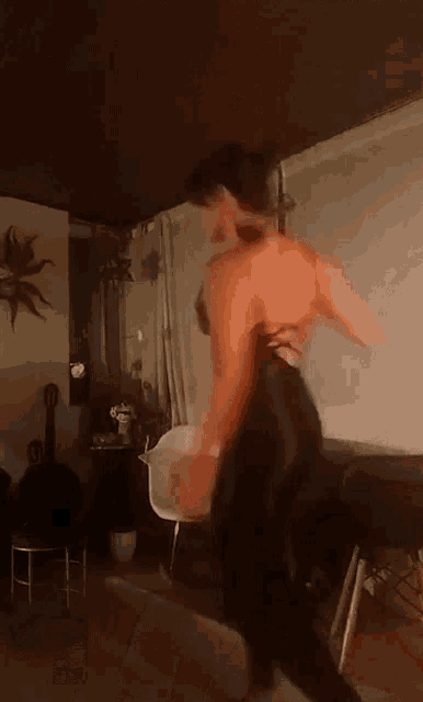 a woman is dancing in a living room with a cross on the wall