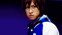 a young man wearing a blue and white jacket looks at the camera with a serious look on his face