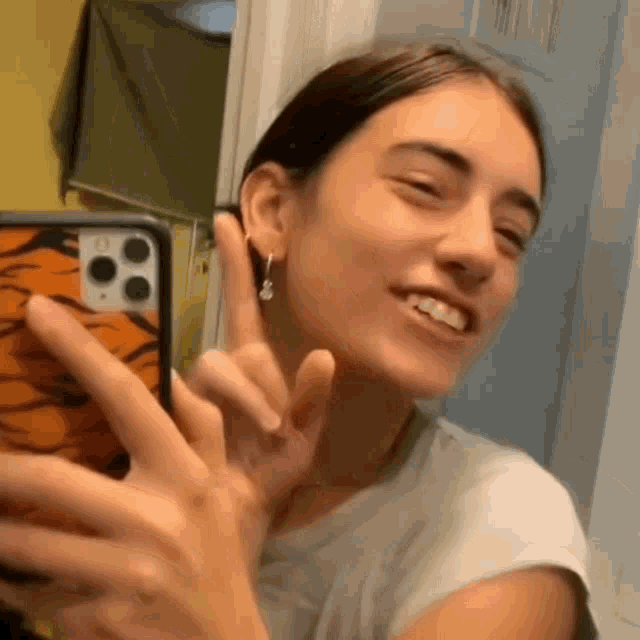 a woman is taking a selfie in front of a mirror with her cell phone .
