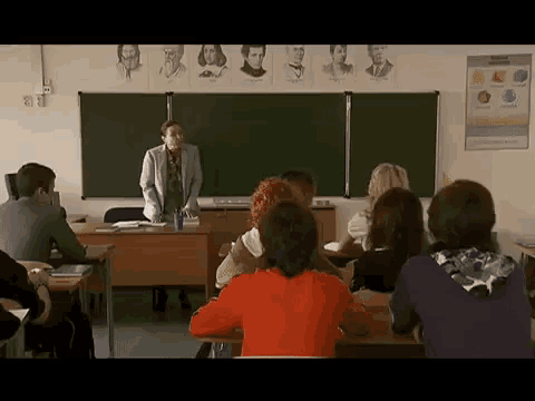 a teacher is standing in front of a classroom full of students .