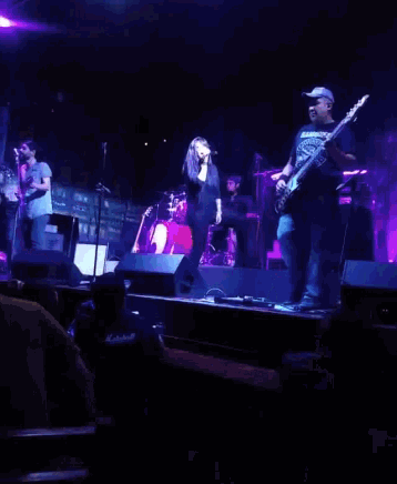 a man playing a guitar on stage with a woman singing