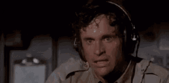 a man wearing headphones is holding his hand to his forehead in a dark room .