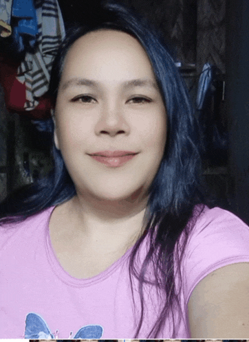 a woman with blue hair is wearing a pink shirt with a butterfly on it