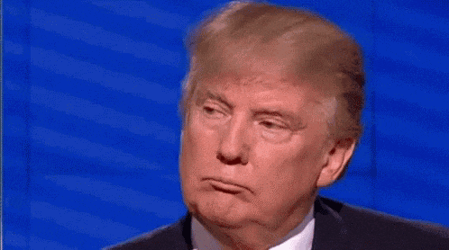 donald trump is making a funny face while pointing his finger at his face .