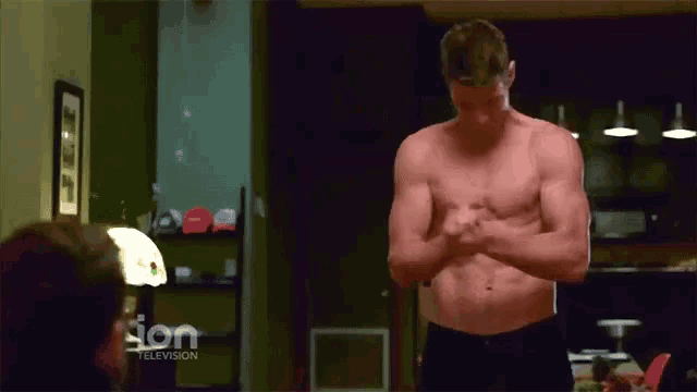 a shirtless man is standing in front of a television screen