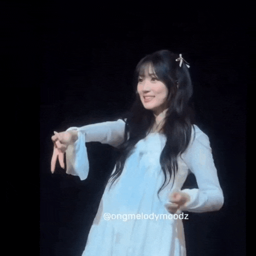 a woman in a white dress with a bow in her hair stands on a stage
