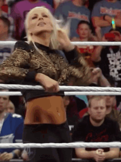 a woman is standing in a wrestling ring with a crowd watching her