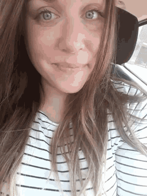 a woman wearing a striped shirt and a hat is smiling