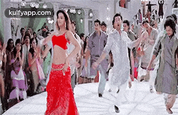 a woman in a red dress is dancing with a man in a white shirt in front of a crowd of people .