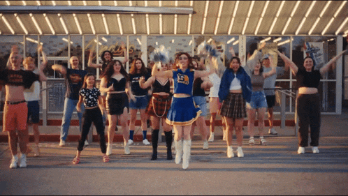 a cheerleader with the number 15 on her top is surrounded by other cheerleaders