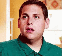 a man in a green shirt looks surprised and shocked