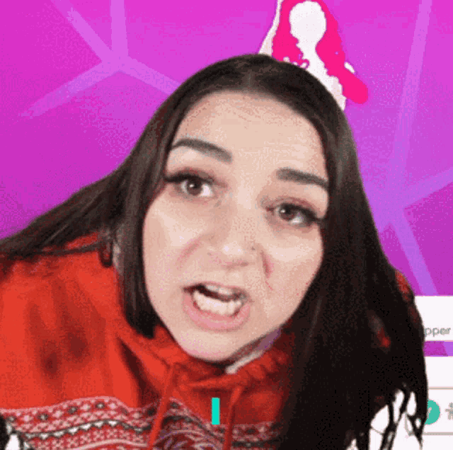 a woman wearing a red sweater and a santa hat makes a funny face