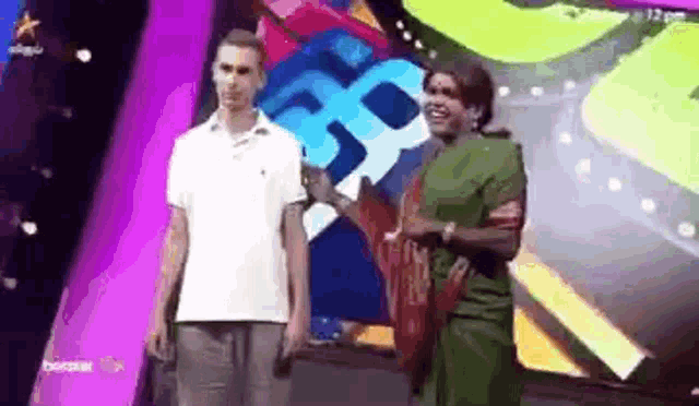 a man and a woman are standing next to each other on a stage . the woman is wearing a green dress .