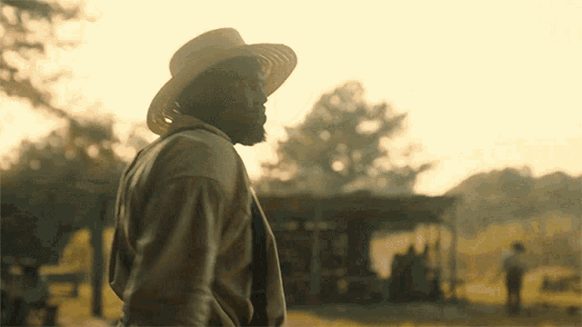 a man in a cowboy hat stands in front of a building