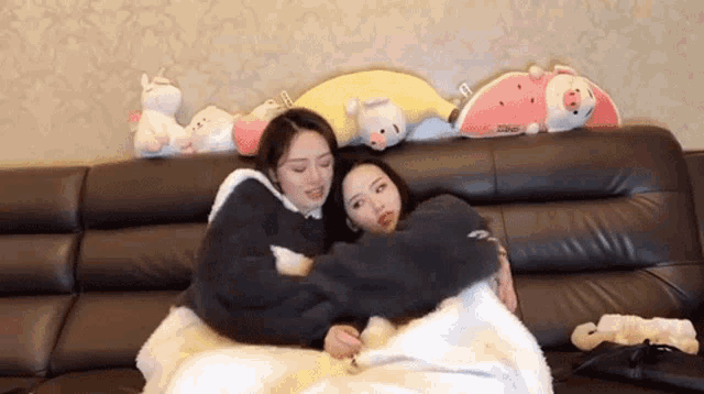two girls are hugging each other on a couch .