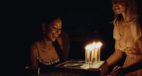 two women are celebrating a birthday with a cake with candles