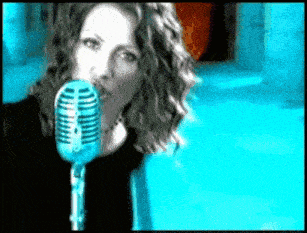 a woman singing into a blue microphone in a video