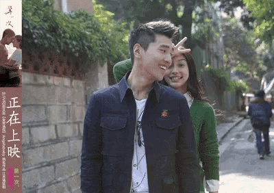 a man and a woman are standing next to each other on a street with chinese writing behind them