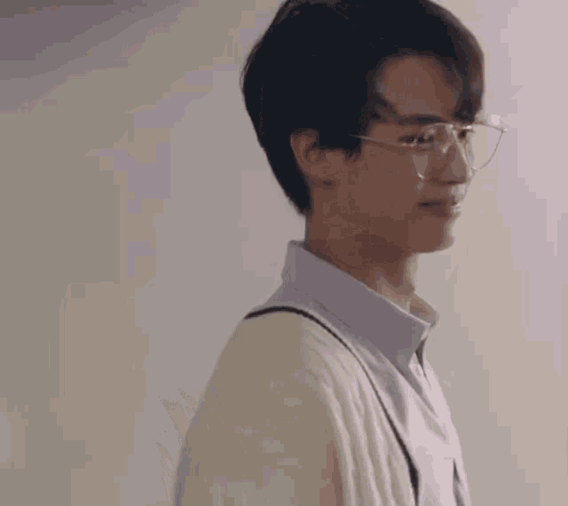 a close up of a person wearing glasses and a cardigan .
