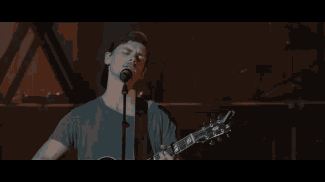 a man is singing into a microphone while holding a guitar .
