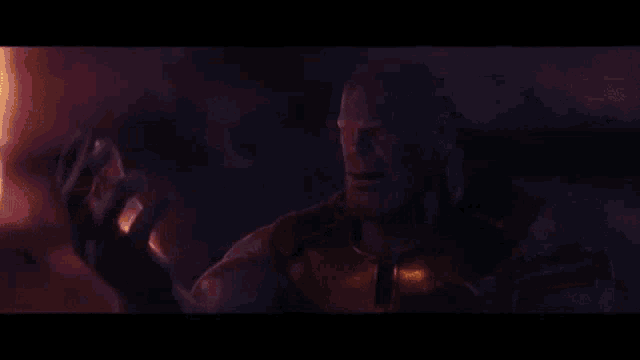 thanos from avengers infinity war is holding a purple object in his hands .