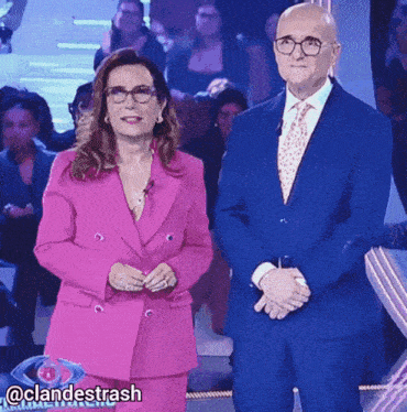 a woman in a pink suit is standing next to a man in a blue suit and tie