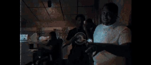 a group of men are standing in a dark room talking to each other .