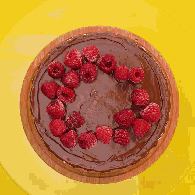 a chocolate cake with raspberries on top of it on a yellow plate