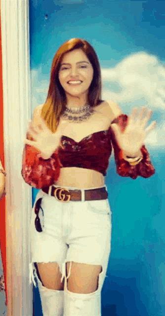 a woman wearing a red crop top and white ripped jeans
