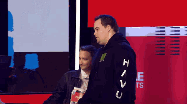 a man wearing a black hoodie with the letter h on the sleeves