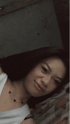 a girl in a white tank top is smiling and looking at the camera