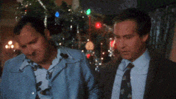 two men are standing in front of a christmas tree .