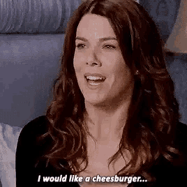 a woman with long hair is smiling and saying `` i would like a cheeseburger ... ''