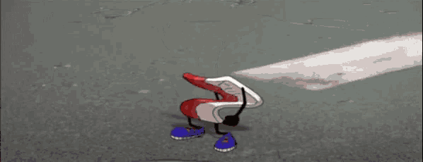 a red and white cartoon character with arms and legs is dancing on the street