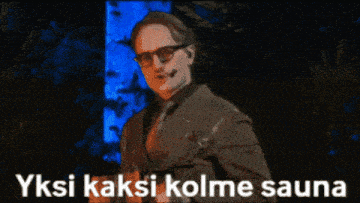 a man in a suit and tie is talking into a microphone with the words yksi kaksi kolme sauna written below him