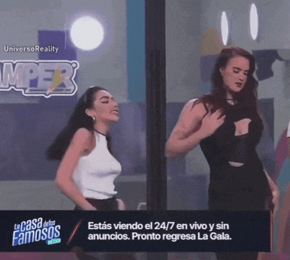 two women are dancing in front of a sign that says " la casa de los famosos "