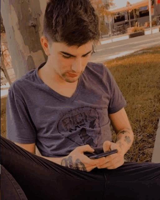 a man wearing a shirt that says rick on it looks at his phone