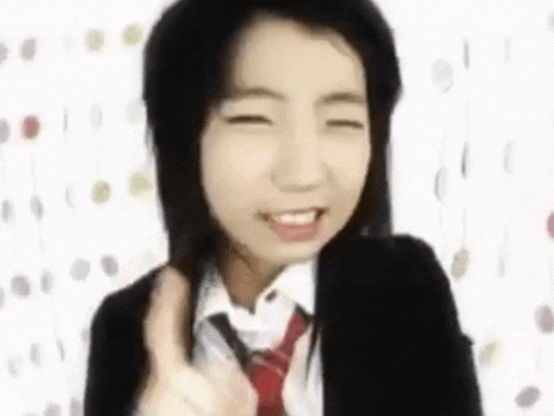 a young girl in a school uniform and tie is giving a thumbs up .