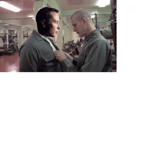 two men in military uniforms are standing next to each other in a warehouse