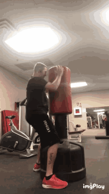a man wearing a pair of shorts that say and1 is squatting on a punching bag