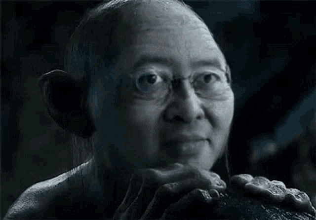a close up of a man wearing glasses and holding something in his hands .